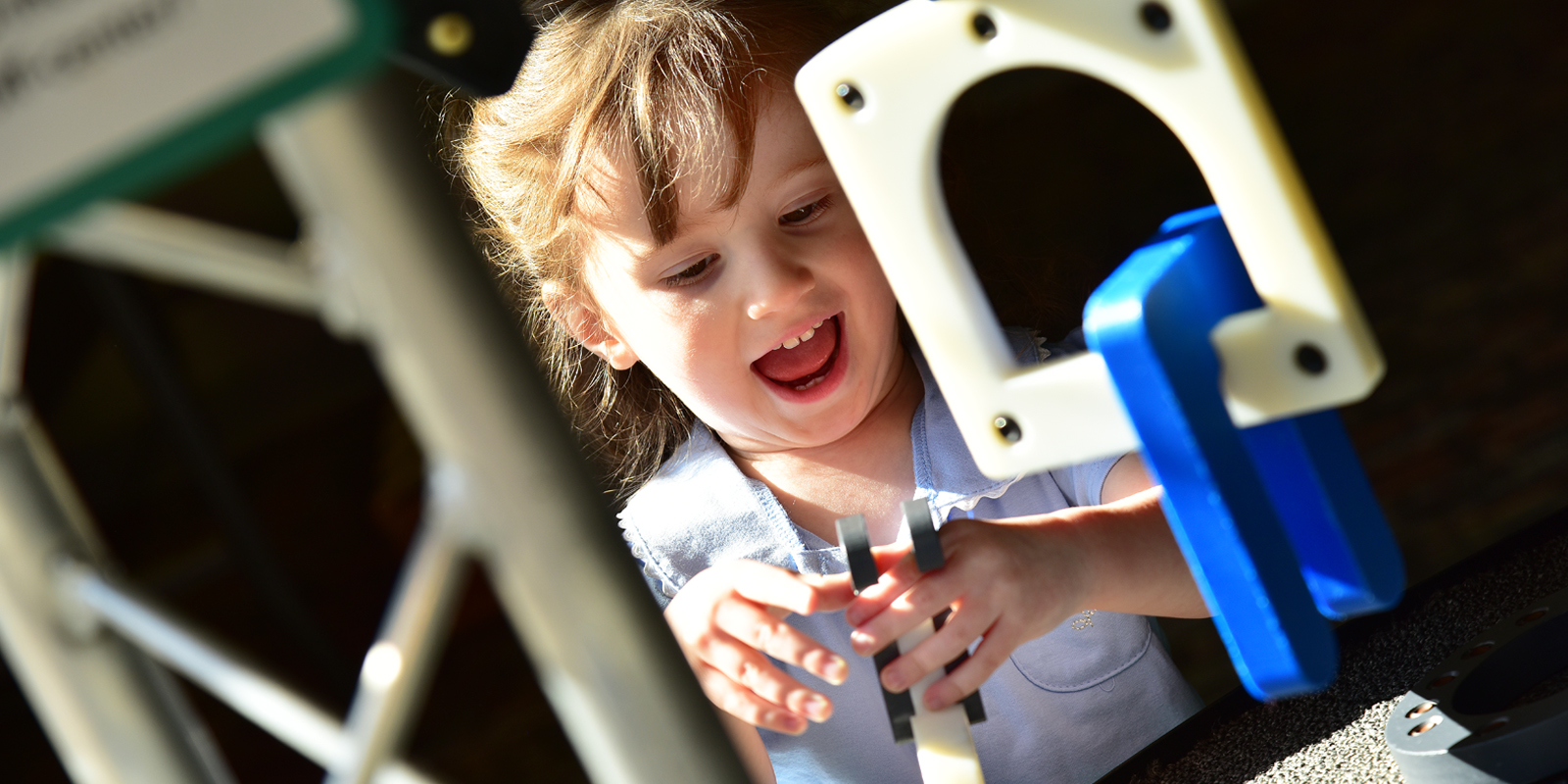 Young girl with light brown hair and light blue shirt playing with plastic building pieces