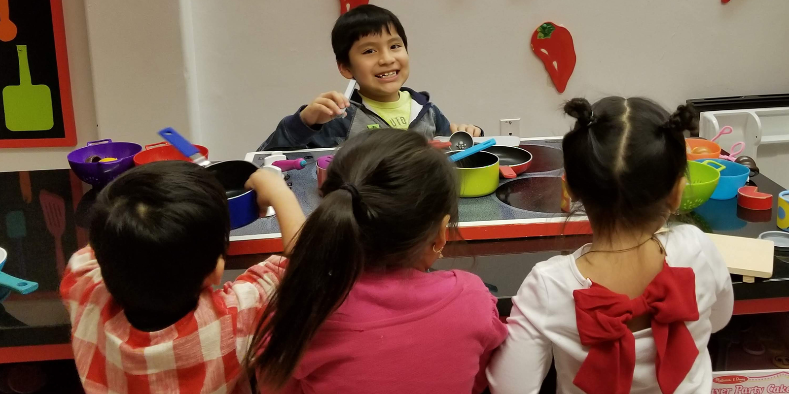 Young children playing with toy kitchen set