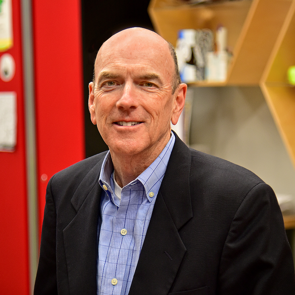 Man wearing dark sports coat and blue dress shirt smiling