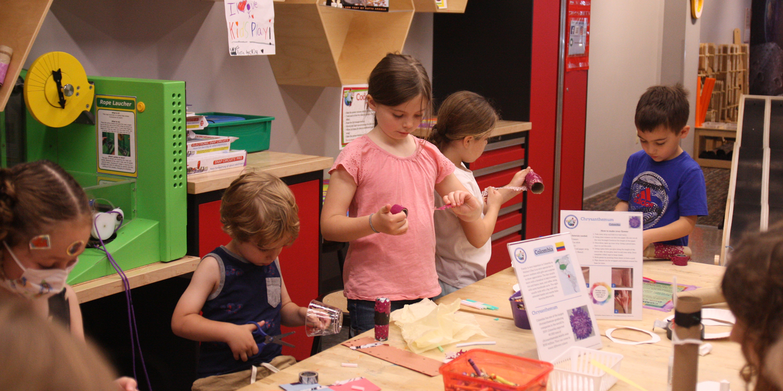 Children standing around a long table doing arts and crafts