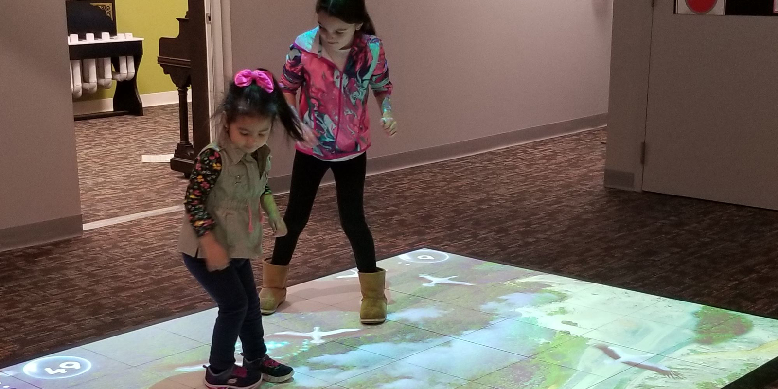 Two young girls dancing on an interactive light up flow mat