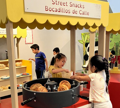 Street Snacks - Bocadillos de Calle booth with snacks and 2 little girls are making snacks under it.