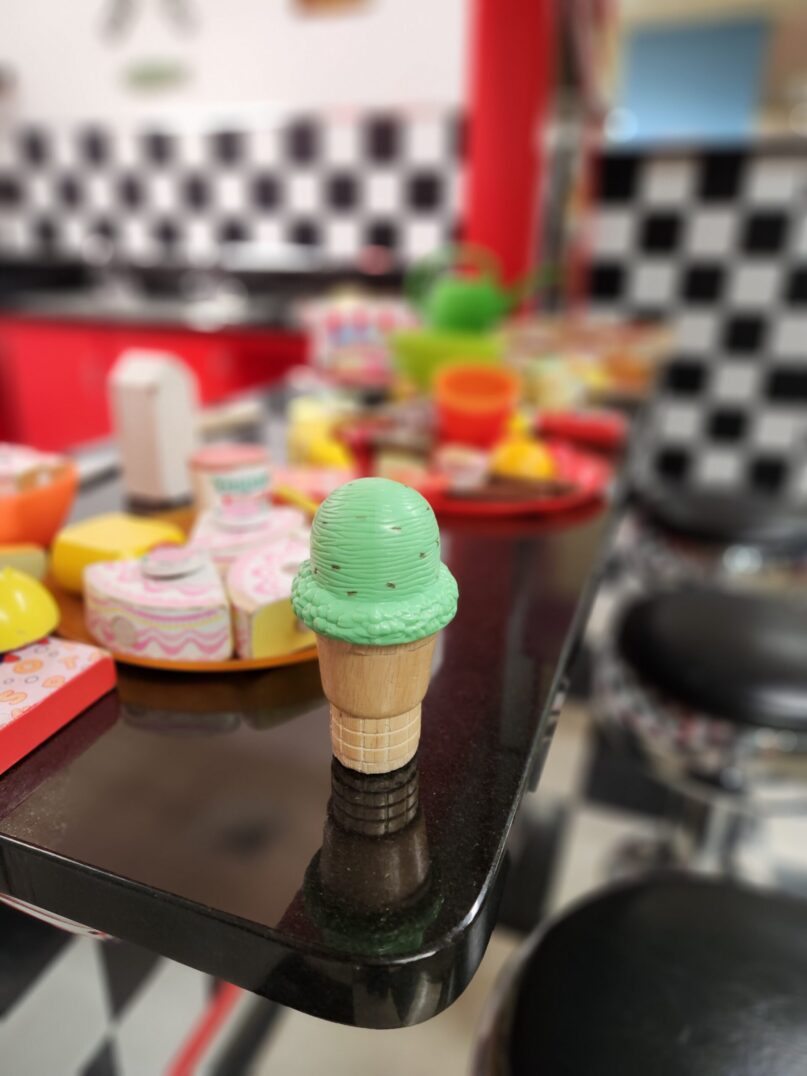 A photo of a plastic toy ice cream cone sitting on the counter of KidsPlay's Diner exhibit.