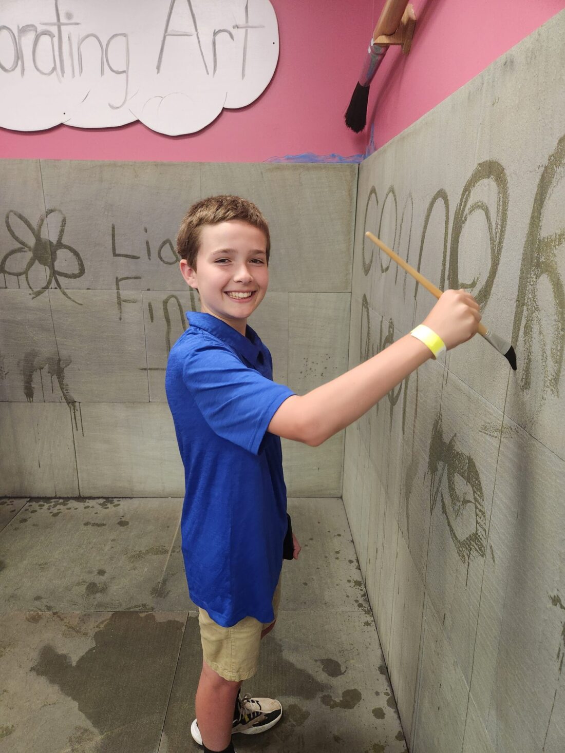 A picture of a smiling boy in a blue shirt playing in the Evaporating Art exhibit.